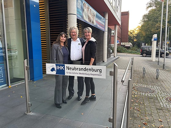 Drei Personen stehen für ein Foto hinter einem Schild der IHK.