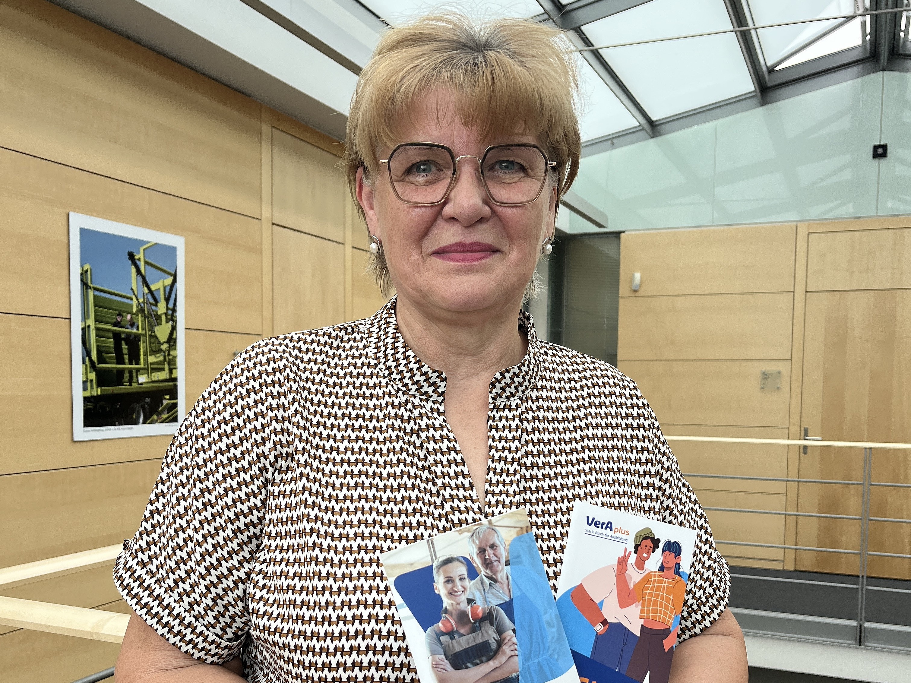 Birgit Augustin hält zwei Flyer zu VerAplus.