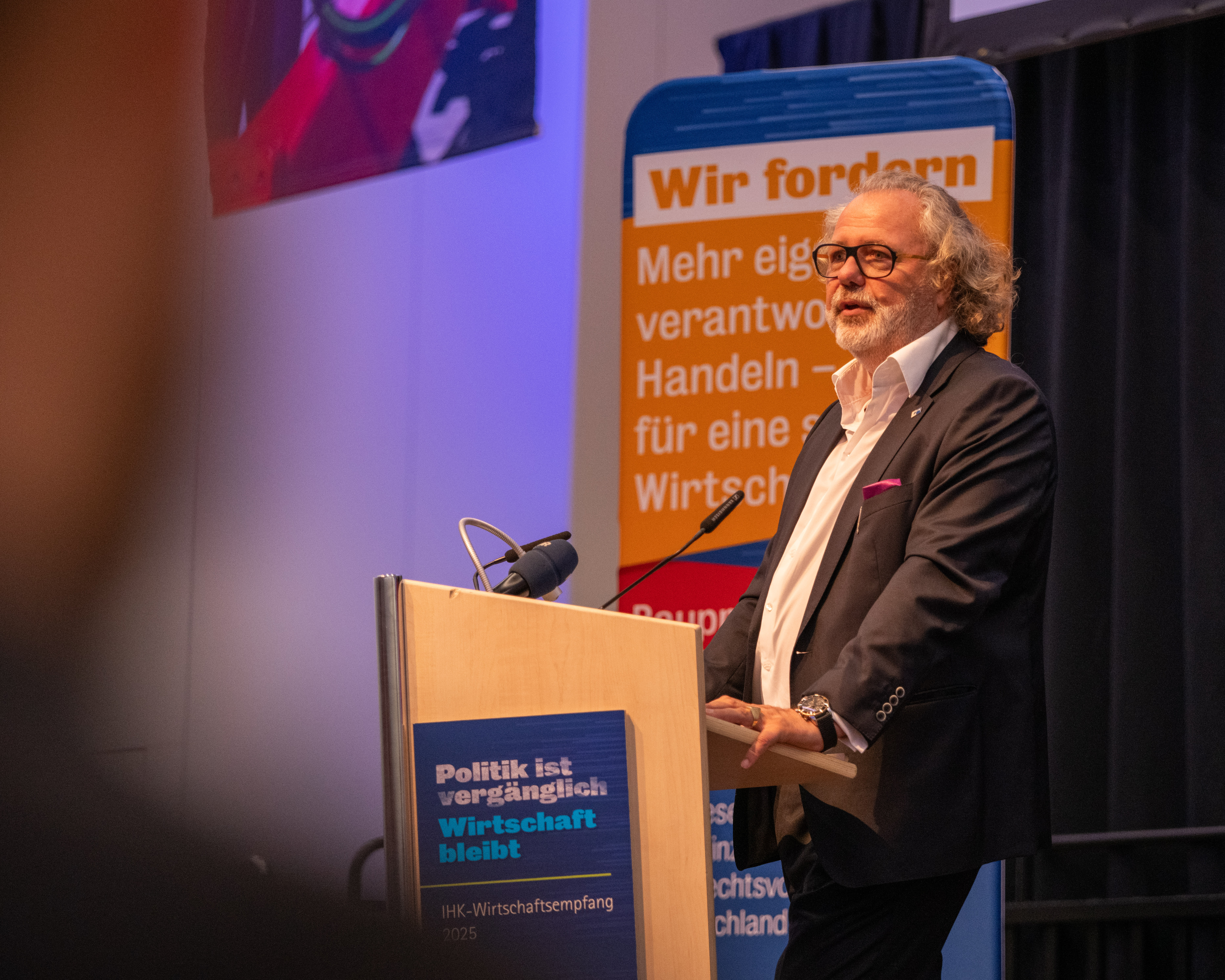 IHK-Präsident Hennige spricht auf einer hell beleuchteten Bühne.
